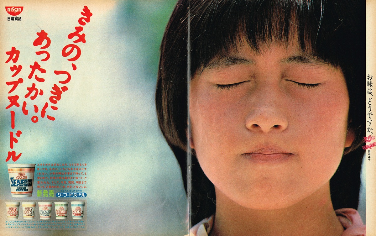 1984年日清食品カップヌードル雑誌広告見開き。右ページに目を閉じた少女・田中ユキの顔のアップ、左ページに「きのつぎ、あったかい。カップヌードル」の赤い縦書きコピー。シーフードヌードル新発売の告知と5種のカップ製品写真。